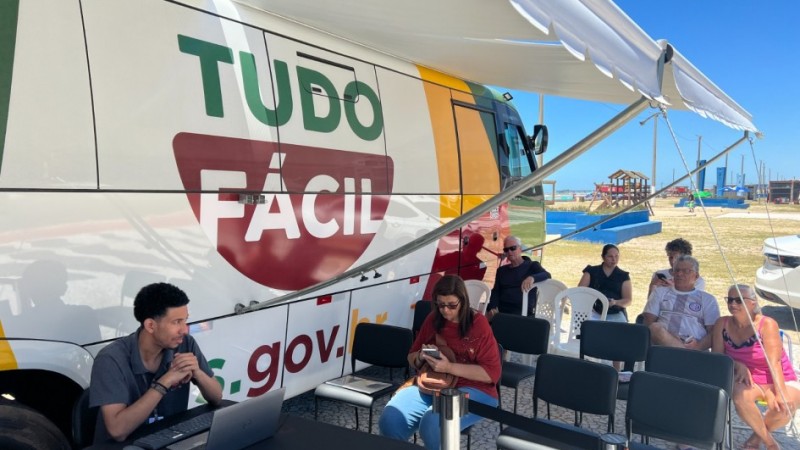 Foto mostra unidade do Tudo F&aacute;cil m&oacute;vel e pessoas aguardando atendimento