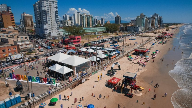 Foto a&eacute;rea mostra tendas da Opera&ccedil;&atilde;o Ver&atilde;o Total na beira da praia com mar em perspectiva.